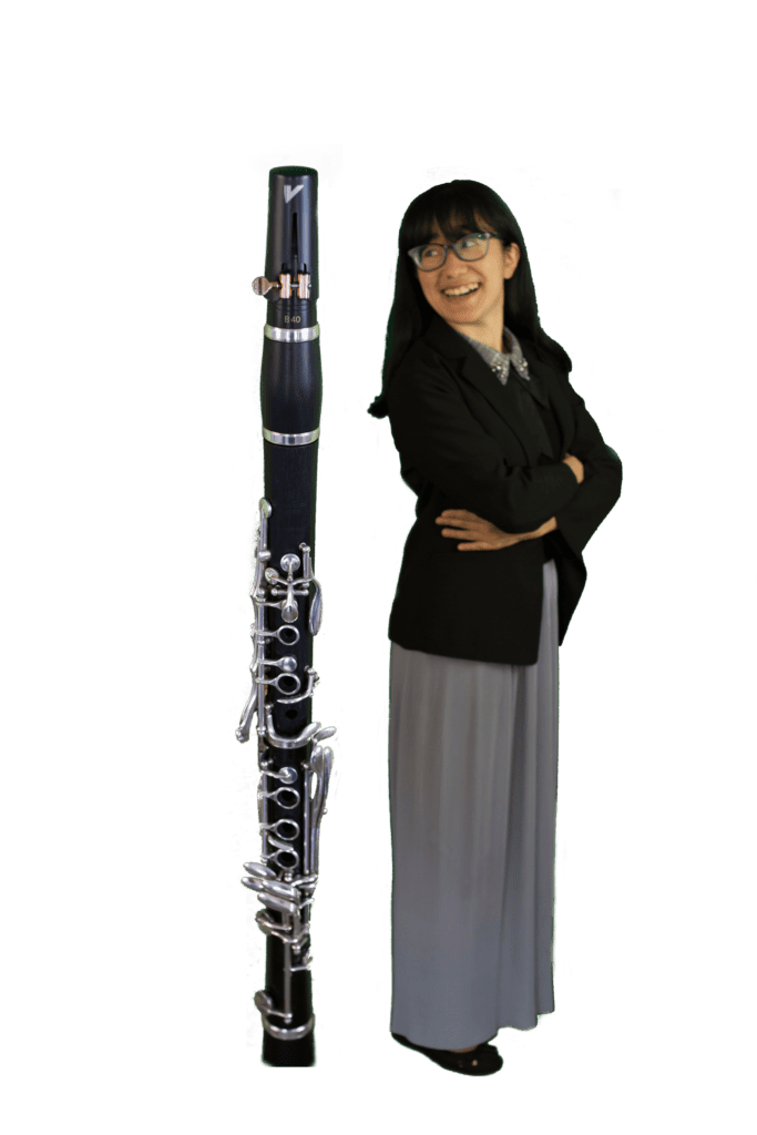 Image of Anna standing next to a clarinet as tall as she is. PNG with transparent background.